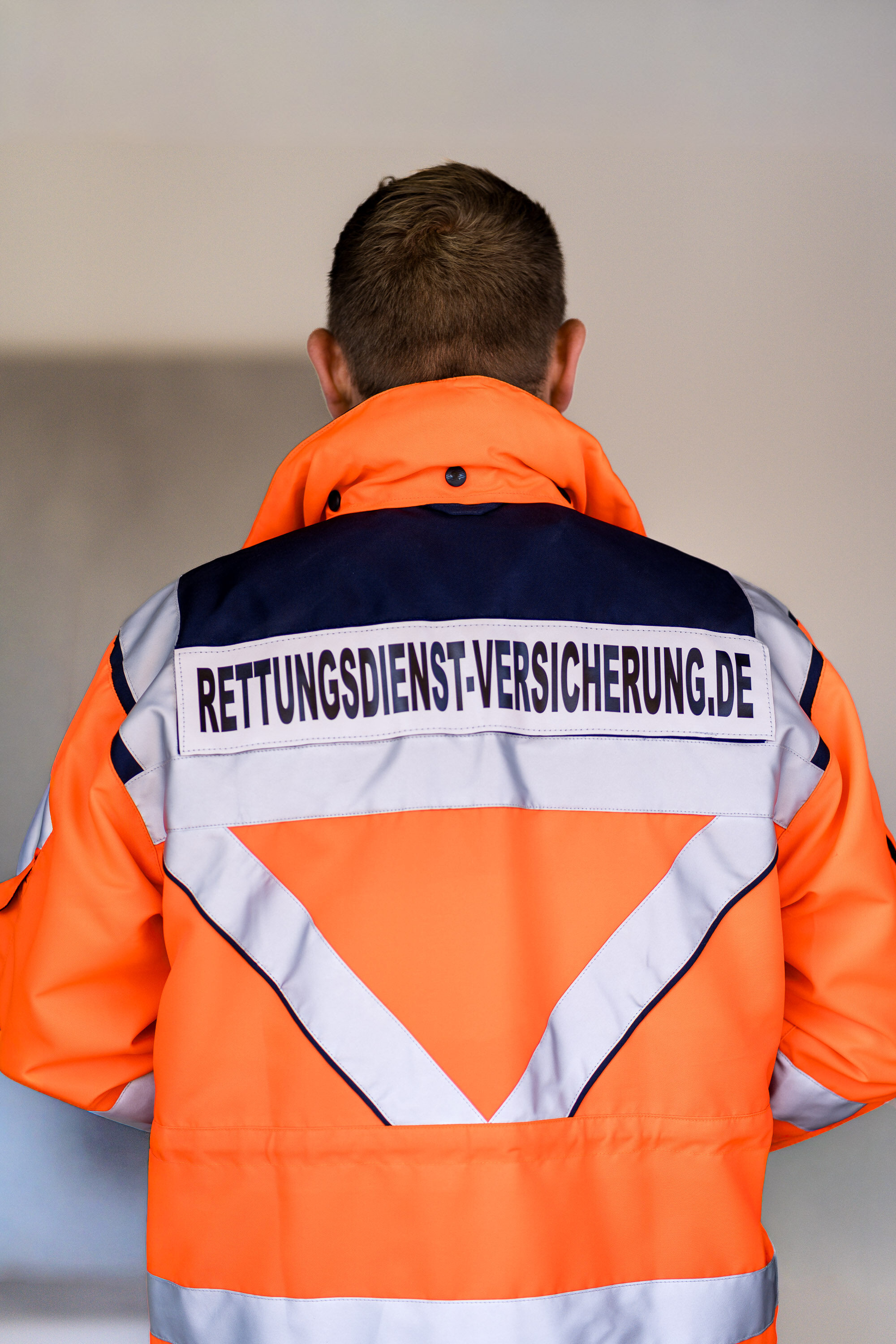 Rückenansicht einer Einsatzjacke mit dem Aufdruck Rettungsdienst-Versicherung.de