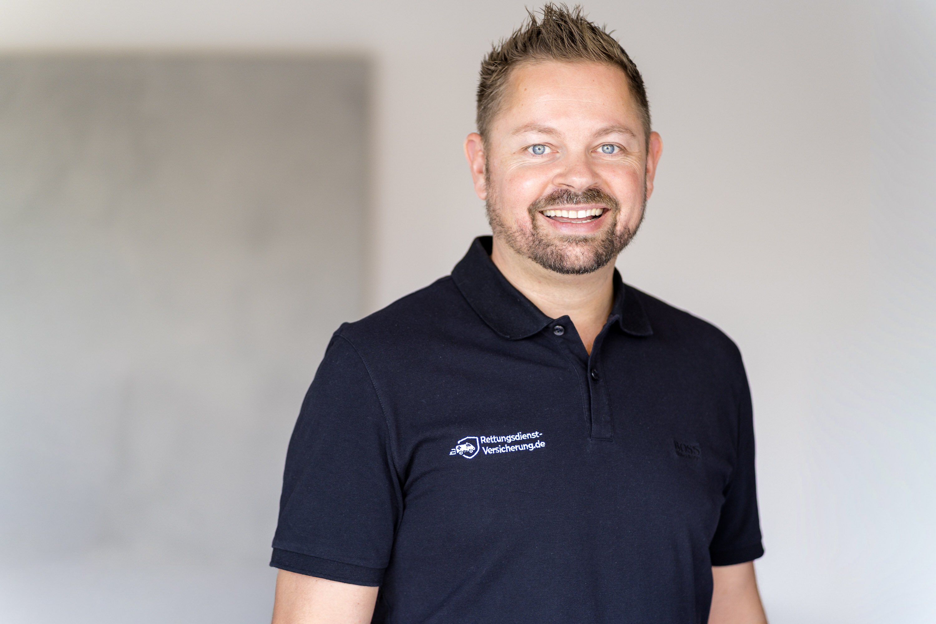 Nikki Pahl im schwarzen Poloshirt mit dem Logo von Rettungsdienst-Versicherung.de